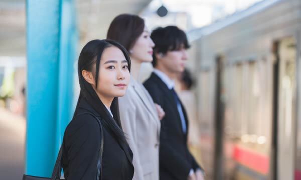 駅で電車を待つ女性