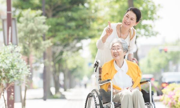 お年寄りの方が座る車椅子を押す女性